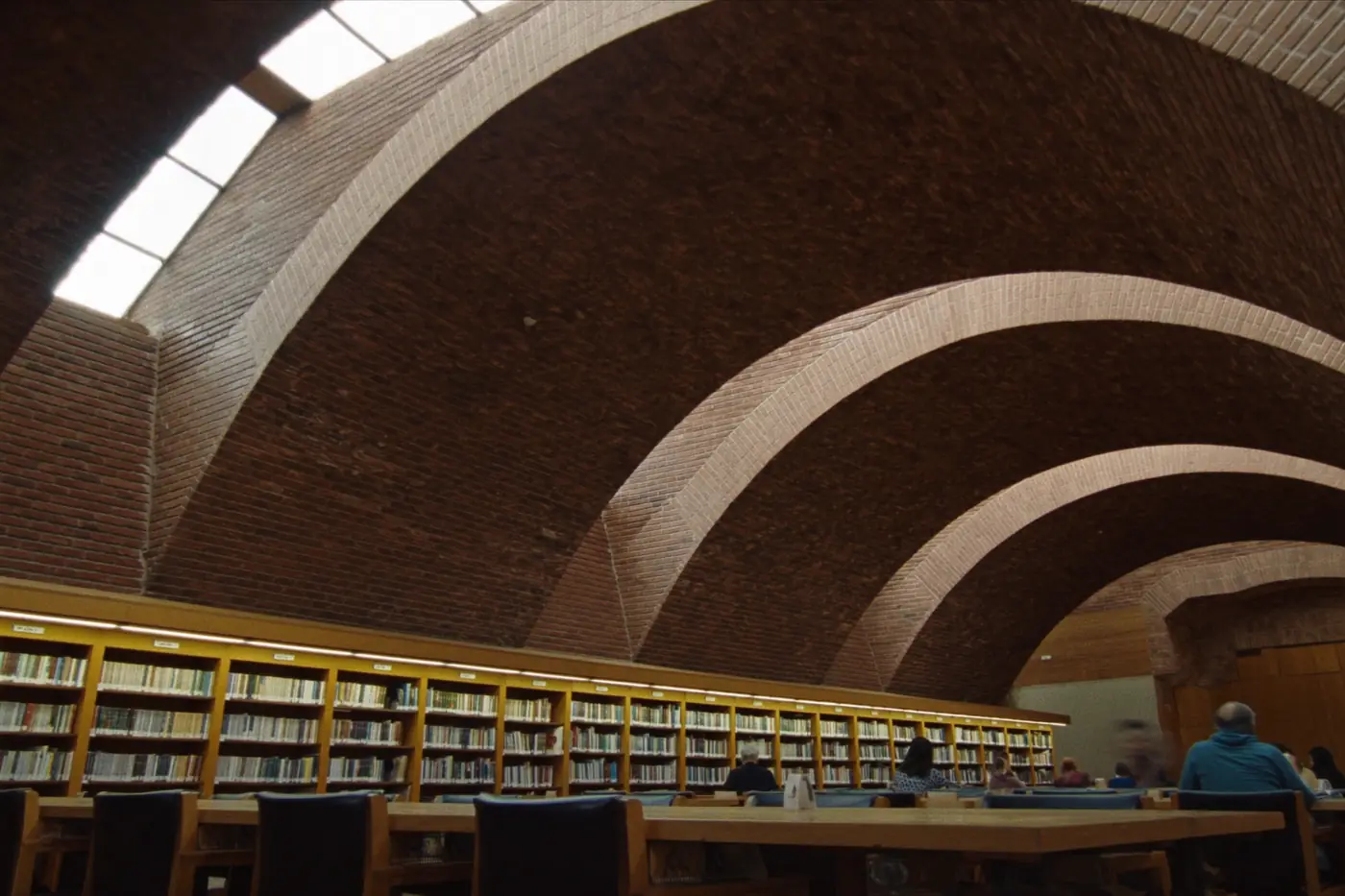 Library interior with tall brick vaults, clerestory light and long oak tables